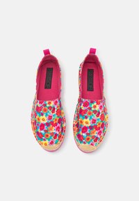 Zapatos tipo slip-on con un fondo rosa vibrante, adornados con una variedad de flores en rojo, amarillo y azul. Suela texturizada y trenzada.