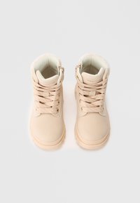 Beige barneboots med polstrede krager, tykke såler, tekstil-lisser og merkedekor på hvit bakgrunn.