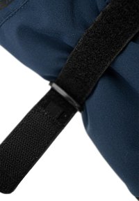 Närbild av svart kardborreband som fäster mörkblå tyg, med fokus på textur och sömdetaljer på båda materialen.