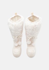 White, fluffy, knee-high boots with a soft texture, elastic opening, and decorative pom-poms. Cream-colored sole with tying detail.