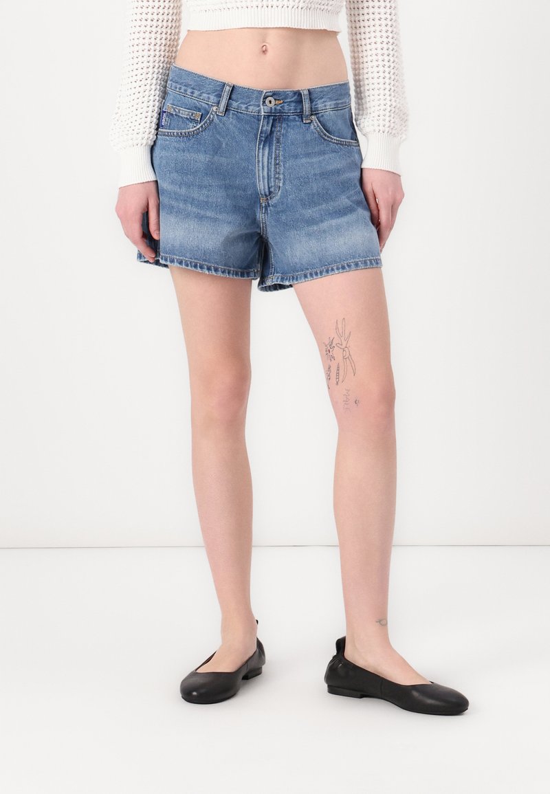 Shorts de mezclilla en azul claro, con un diseño clásico que incluye un bolsillo frontal, dobladillo recto y una textura deslavada. Combinados con bailarinas negras.