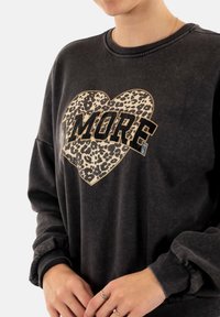 Felpa grigia con un cuore a stampa leopardata e la scritta "AMORE". Vestibilità rilassata con polsini a costine e una texture morbida e spazzolata.