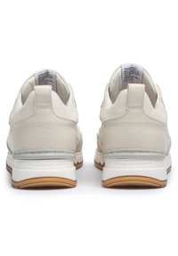 Baskets blanches avec une tige en cuir texturé, des accents lisses, un col rembourré et une semelle en caoutchouc avec une bande de roulement brun clair.