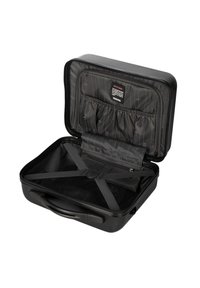 Valise rigide noire avec une fermeture éclair. L'intérieur est doté de sangles élastiques, de multiples poches et d'un doublure texturée. Design compact.