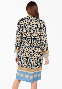 Bata de leopardo en beige, con manchas negras y azules. Acentos de satén azul con una banda dorada de "FASHION" y un patrón de corazones en el dobladillo.