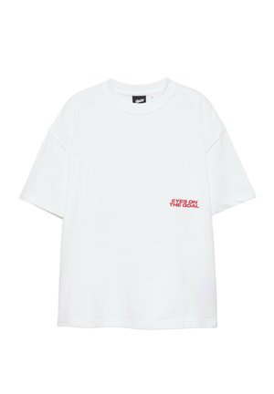 Weißes T-Shirt mit kurzen Ärmeln und rotem Text "EYES ON THE GOAL" unten rechts auf der Vorderseite und einem schwarzen Markenetikett innen im Kragen.