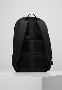 Zaino nero con spallacci imbottiti e pannelli in rete sul retro. Presenta un design slanciato con spallacci regolabili e hardware resistente.