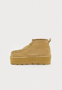 Sari brūni zamšaini potīšu zābaciņi ar apaļu purngalu, šuvju detaļām un biezu, profilētu zoli. Iekļauj nelielu papēdi un aizmugurē esošu cilpu.