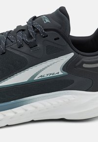 Scarpa da corsa nera con tomaia in mesh, accenti grigi, una intersuola bianca e lacci a contrasto. Presenta un design aerodinamico con pannelli testurizzati.