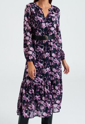 Květinové šaty tmavě modré barvy s růžovými a bílými květy, s dlouhými rukávy, výstřihem do V, černým páskem se zlatou sponou a sukni s volány.