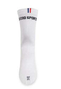 Calcetín deportivo blanco con textura acanalada, que presenta el logo negro "LE COQ SPORTIF" y franjas rojas y azules en el borde superior.