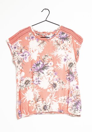 Perzikkleurige korte mouw blouse met paars, wit en beige bloemenprint, gehaakte kant op de schouders, ronde halslijn, hangend aan een zwarte hanger.