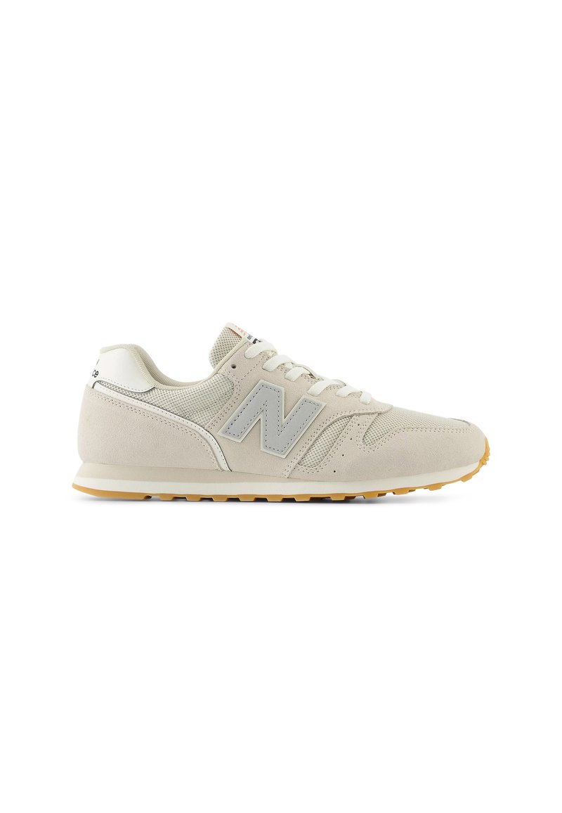 Zapatillas de ante y malla en color beige claro, con un logotipo gris, cordones planos y una suela de goma con un patrón texturizado.