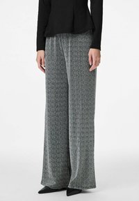 Platām biksēm ar melnu un baltu punktiņu rakstu. Mīksts audums ar vaļīgu piegriezumu. Kombinētas ar melnu topu un smailiem melniem apaviem.