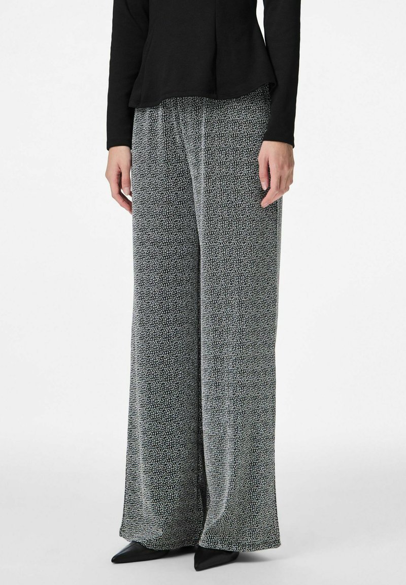 Platām biksēm ar melnu un baltu punktiņu rakstu. Mīksts audums ar vaļīgu piegriezumu. Kombinētas ar melnu topu un smailiem melniem apaviem.