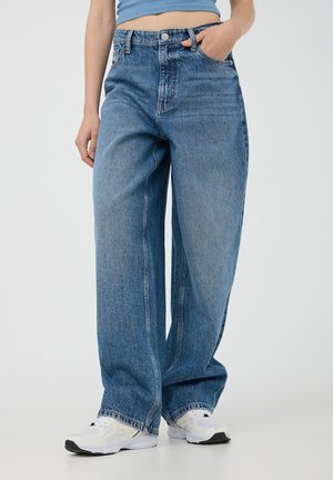 Jeans in denim chiaro a vita alta, con una vestibilità rilassata, gamba dritta, texture sbiadita, cinque tasche e dettagli di cucitura visibili.