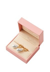 Pendientes colgantes en tono dorado con perlas blancas en forma de lágrima, presentados en una caja de joyería rosa con un suave forro beige en el interior.