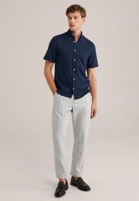 Camisa de botones navy de manga corta, pantalones gris claro a cuadros y mocasines negros. Tela suave, ajuste entallado y botones en contraste.