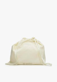 Sac en tissu couleur crème avec cordon de serrage, lanières longues en ruban, légèrement froncé en haut, sur fond blanc.