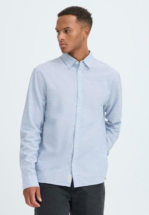 Hellblaues Hemd mit Knopfleiste, strukturierter Stoff, lange Ärmel und klassischer Kragen. Knöpfe an der Vorderseite und ein kleines Etikett am Saum.