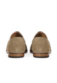 Mocassins en daim beige avec des talons arrondis, des semelles en bois et un minimalisme dans le design. L'intérieur présente une doublure à motifs contrastants.