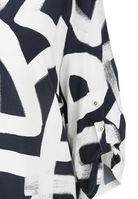 Blaue und weiße, abstrakt gemusterte Bluse. Hat einen lockeren Schnitt, hochgerollte Ärmel mit Druckknöpfen und eine glatte, leichte Stofftextur.