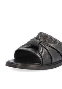 Sandale noire à doigt ouvert, avec dessus en cuir plissé et large bride nouée sur le dessus du pied, semelle plate et semelle intérieure rembourrée.