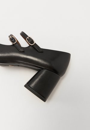 Czarne buty na blokowym obcasie z elegancką skórzaną cholewką, dwiema regulowanymi ramiączkami i metalowymi klamrami. Teksturowany obcas kontrastuje z gładką powierzchnią.