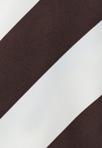 Braun-weißer, diagonal gestreifter Stoff mit glatter Textur und leichtem Glanz, der kontrastierende Farben in einem auffälligen Muster zeigt.