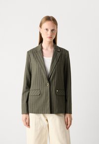 Olive roheline triibuline bleiser, millel on nurgelised kraed, üks nupp ja kaks esimat pockets. Valmistatud tekstuursest kangast, näidates hästiistuvat lõiget.