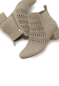 Bottines beiges à talon compensé, en daim doux, ornées de motifs triangulaires découpés et d'un détail de fermeture éclair sur le côté.