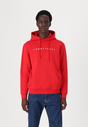 Red hooded sweatshirt with a kangaroo pocket, featuring a white "TOMMY JEANS" logo across the chest. Made of soft fabric with ribbed cuffs.
