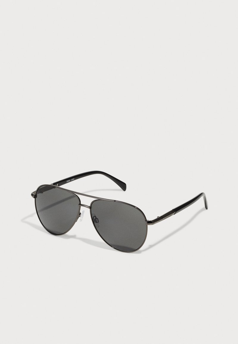 Ochelari de soare tip aviator cu lentile întunecate, cadru subțire din metal negru și brațe din plastic negru. Bureți ajustabili pentru nas pentru confort.