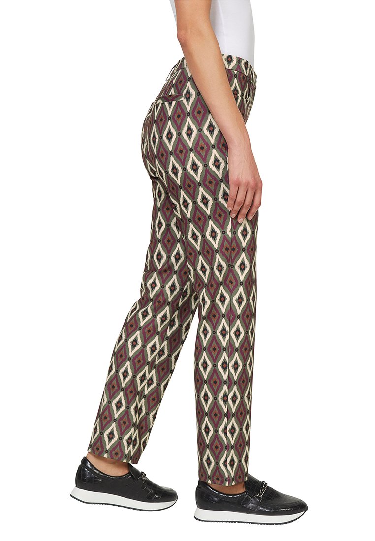 Spodnie w brązowe, kremowe i purpurowe romby; prosty krój nogawek z bocznymi kieszeniami; noszone z czarnymi sneakersami.