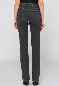 Jean oscuro con un ajuste slim, material de mezcla de algodón, cinco bolsillos y una etiqueta de cuero en la cinturilla. Diseño de pierna recta.