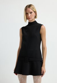 Schwarzes ärmelloses Kleid mit hohem Kragen, schwingendem Rock und breitem Taillengürtel. Aus glattem Stoff gefertigt, mit einem mittigen Nahtdetail.