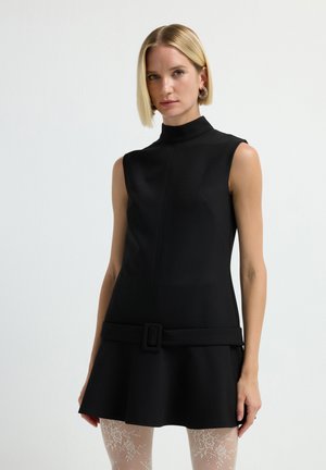 Robe noire sans manches avec un col haut, une jupe évasée et une large ceinture en accent. Fabriquée en tissu lisse, elle présente un d�étail de couture central.