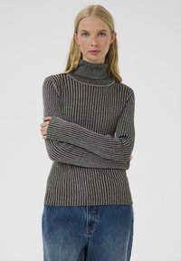 Maglione grigio a collo alto con un design aderente, caratterizzato da maniche lunghe e una finitura testurizzata, abbinato a jeans in denim blu.