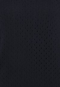 Schwarzer gestrickter Stoff mit einem strukturierten Muster und kleinen Löchern, die gleichmäßig über die Oberfläche verteilt sind. Weiches und dehnbares Material.