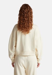 Felpa oversized beige chiaro con polsini e orlo a costine, caratterizzata da una vestibilità rilassata. Texture morbida e design confortevole per un abbigliamento casual.