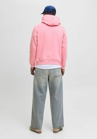 Felpa con cappuccio rosa dal taglio rilassato, abbinata a jeans in denim azzurri a gamba larga e scarpe beige. Design semplice e casual.