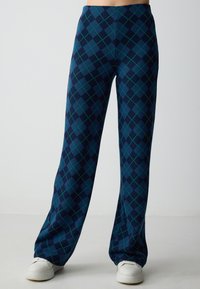 Pantaloni a gamba larga in navy con un motivo argyle verde e blu. Realizzati in tessuto testurizzato, presentano un alto punto vita e una vestibilità comoda.