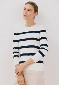 Maglione a righe in bianco con righe orizzontali blu navy, scollo rotondo e maniche a tre quarti. Texture morbida.