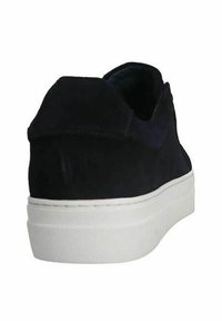 Scarpa nera in suede senza lacci con punta arrotondata, tomaia testurizzata e suola in gomma bianca spessa. Design minimalista senza hardware visibile.