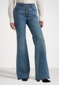 Høytlivede, blå denim flared jeans med knappestolpe, teksturert stoff og en subtil vask. Har vide ben og kontrasterende sømmer.