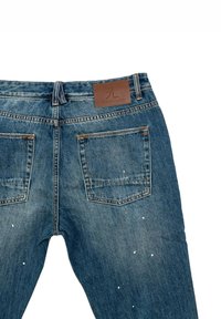 Vaqueros de denim azul con corte recto, que presentan una etiqueta de piel marrón, dos bolsillos traseros y detalles de salpicaduras de pintura blanca.