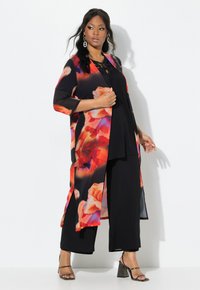 Lange, zwarte bloemenkimono met oranje en roze rozenpatronen, met driekwartmouwen en een lichtgewicht, transparante stof. Gedragen over een zwarte outfit.