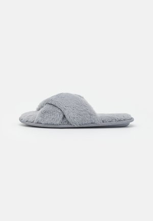 Chausson ouvert gris clair à fourrure avec des lanières croisées et une semelle plate, sur un fond blanc uni.