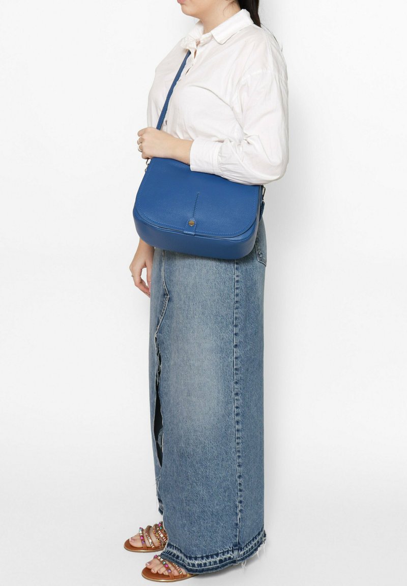 Borsa a tracolla in pelle blu con forma arrotondata, superficie testurizzata, tracolla singola regolabile e un semplice dettaglio in metallo dorato.