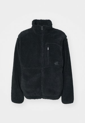 Black fleece jacket with a high collar, full front zip, and a chest pocket. Features a textured, soft surface and logo on the pocket.